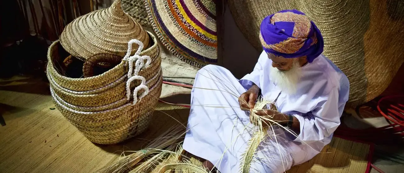 Omani demonstra um do artesanato tradicional do Omã no Festival anual Muscat