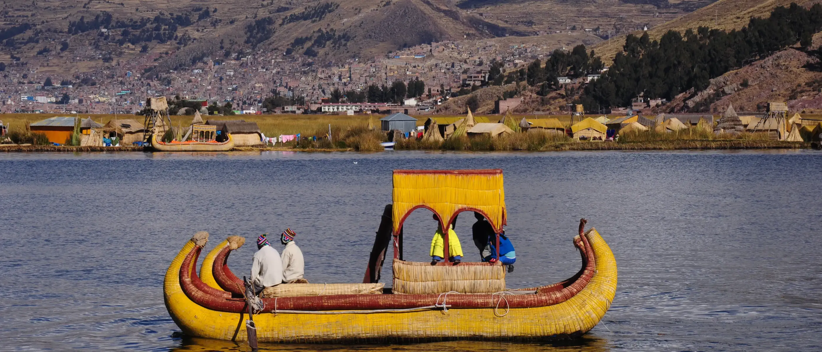Barco navegando pelo Lago Titicaca com montanhas no fundo