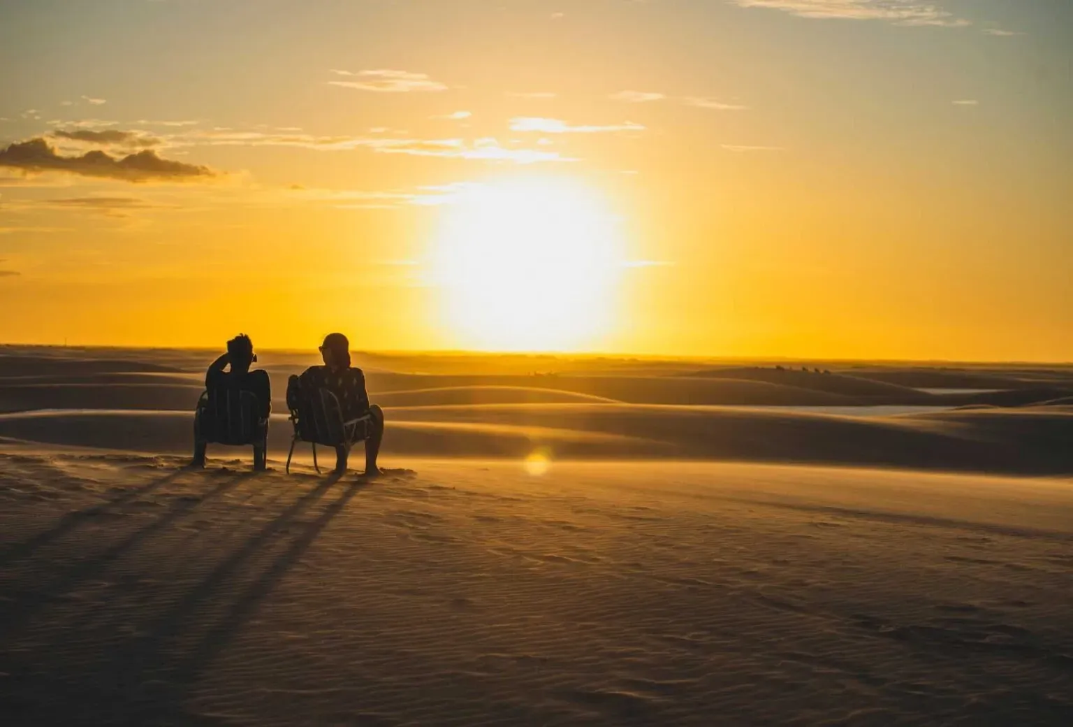Duas pessoas olhando para o por do sol nos Lençois Maranhenses